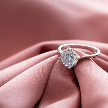 silver diamond ring on a pink cloth